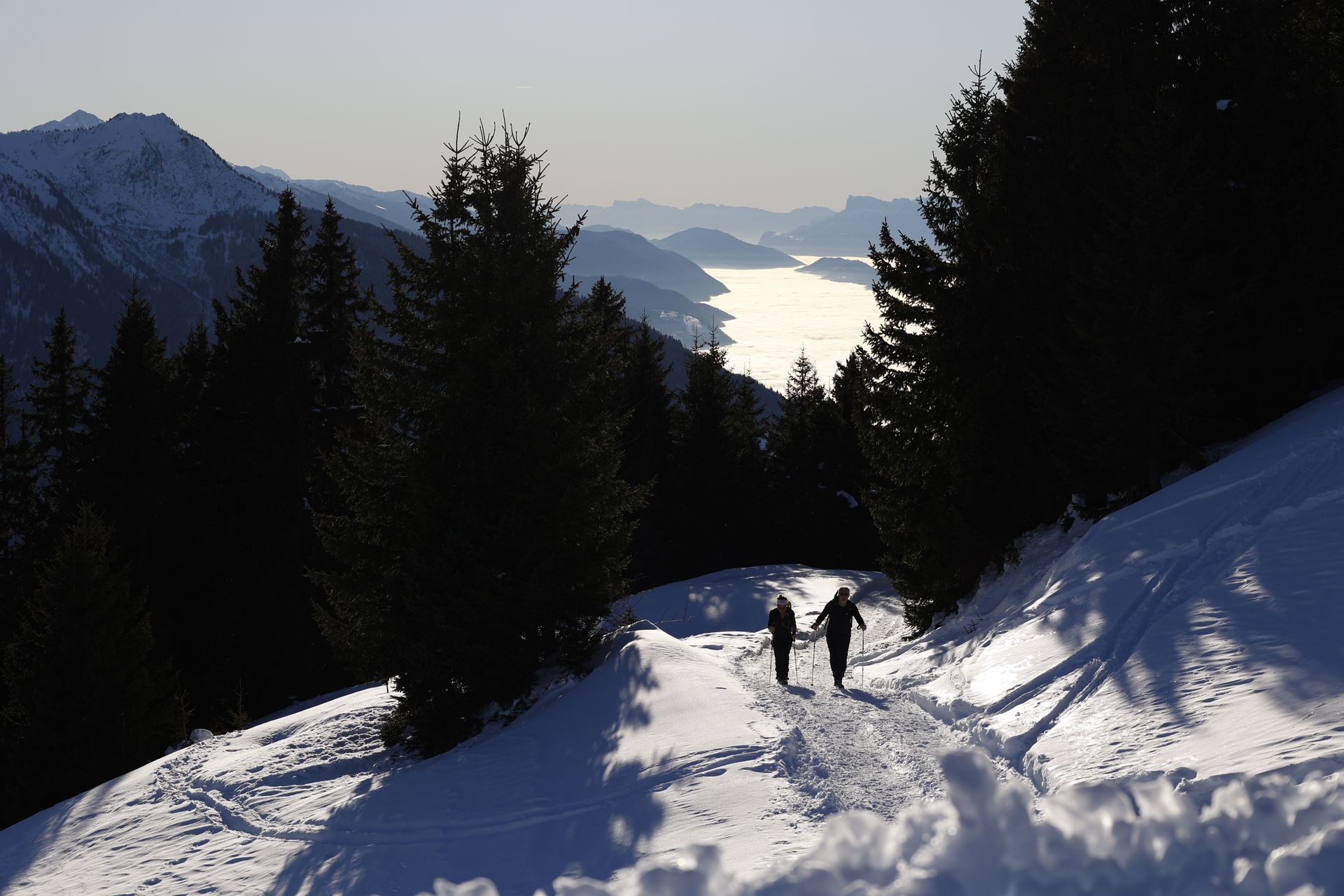 Wandelaars op een besneeuwd bergpad boven een wolkenzee